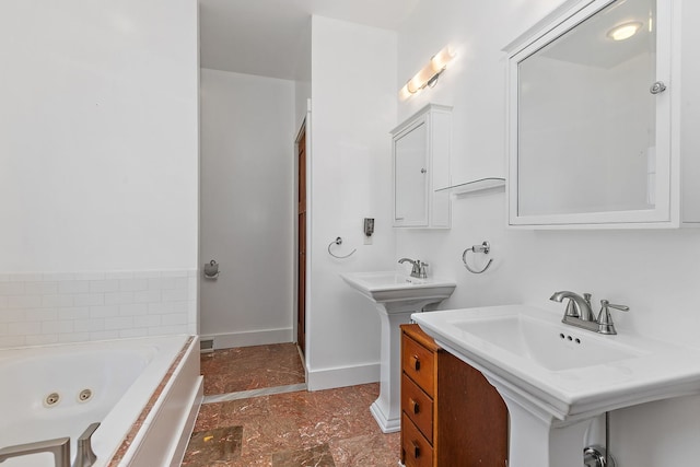 bathroom with dual sinks and a bathtub