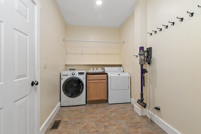 clothes washing area with cabinets and separate washer and dryer