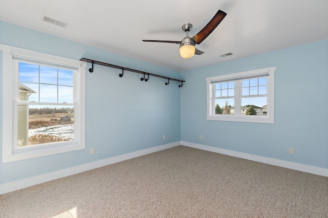 carpeted empty room with ceiling fan and plenty of natural light