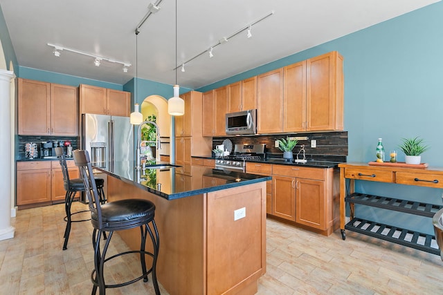 kitchen featuring appliances with stainless steel finishes, sink, a kitchen breakfast bar, hanging light fixtures, and a center island with sink