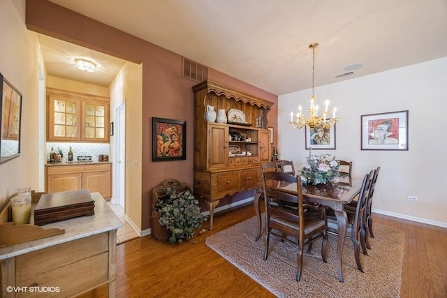 dining area with hardwood / wood-style floors and a chandelier