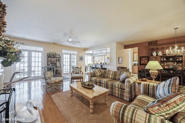 living room with ceiling fan with notable chandelier, hardwood / wood-style floors, and french doors