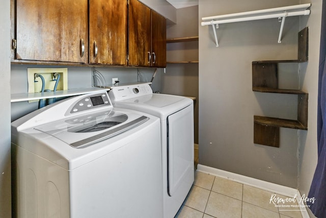 clothes washing area with cabinets, separate washer and dryer, and light tile patterned floors