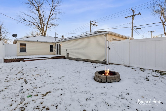 snow covered rear of property with an outdoor fire pit