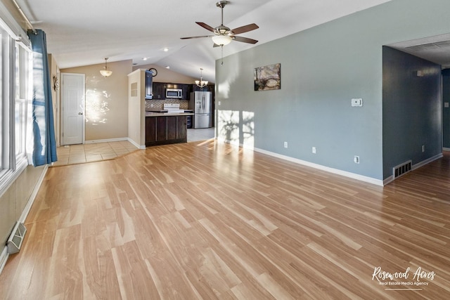 unfurnished living room featuring ceiling fan, a wealth of natural light, light hardwood / wood-style flooring, and vaulted ceiling