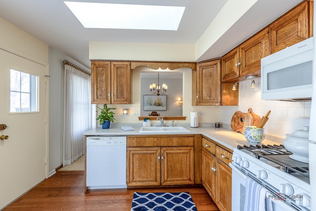 kitchen featuring white appliances, brown cabinets, and a sink