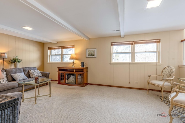 sitting room featuring visible vents, beamed ceiling, and carpet flooring