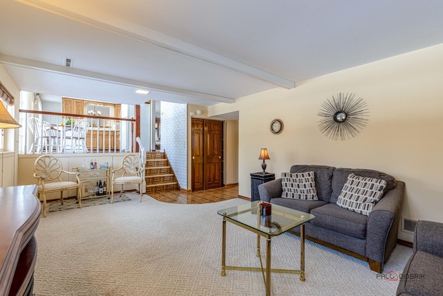 carpeted living area with stairway, beamed ceiling, and visible vents