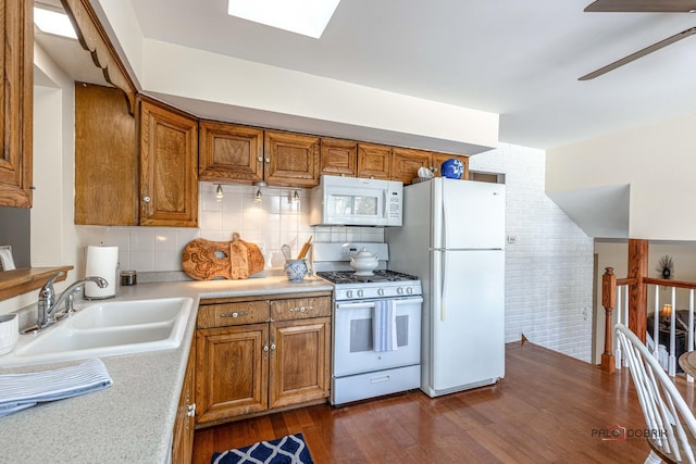 kitchen featuring brown cabinets, white appliances, light countertops, and a sink