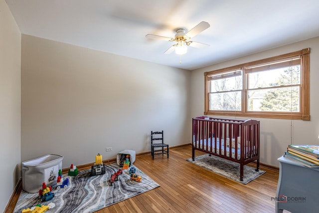 bedroom featuring wood finished floors, a ceiling fan, and baseboards