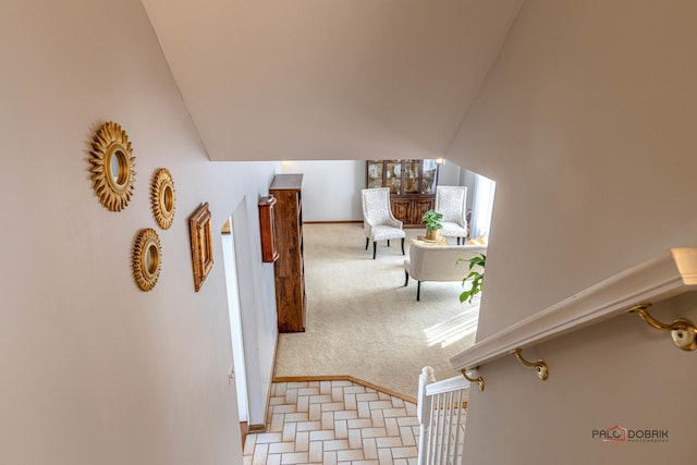 hall with lofted ceiling, stairway, and light colored carpet