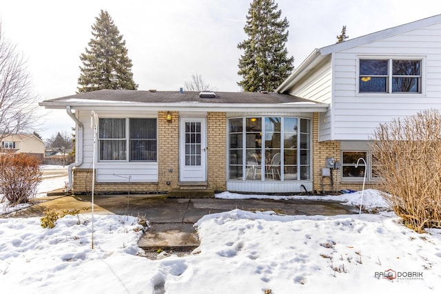 snow covered property featuring brick siding