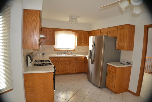 kitchen with stainless steel fridge, gas range, sink, decorative backsplash, and range hood