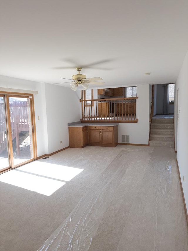 unfurnished living room featuring baseboards, visible vents, ceiling fan, and light colored carpet