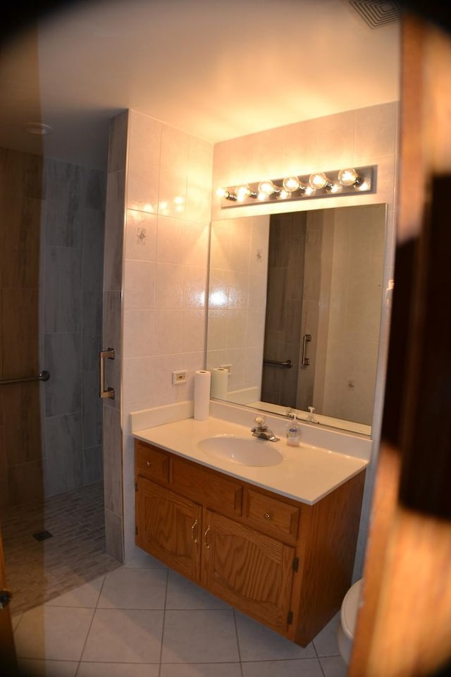 bathroom featuring tile patterned flooring, vanity, a shower, and tile walls