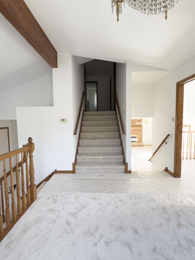 stairs with carpet floors, vaulted ceiling with beams, and baseboards