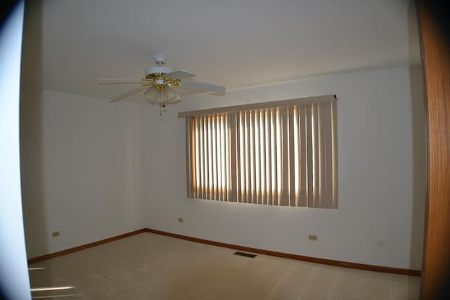 carpeted spare room with ceiling fan