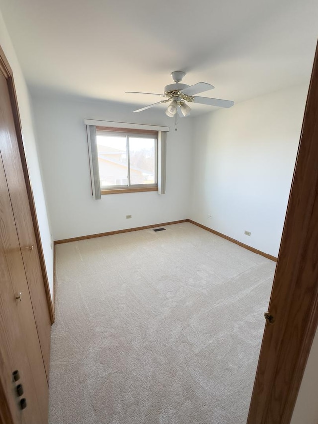 unfurnished bedroom with baseboards, a ceiling fan, visible vents, and light colored carpet