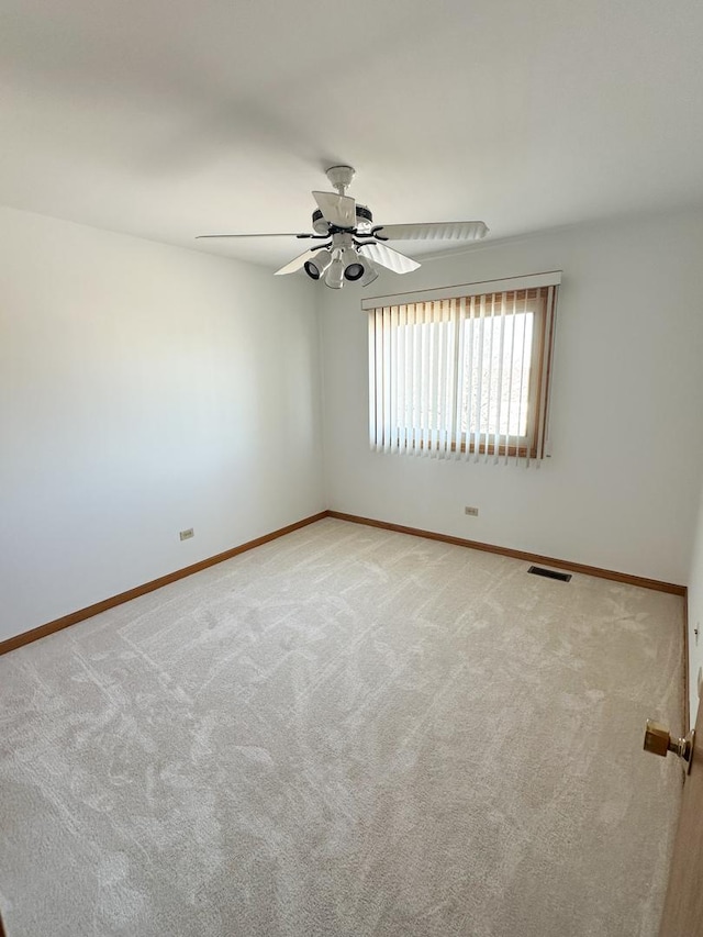 empty room featuring a ceiling fan, carpet, visible vents, and baseboards