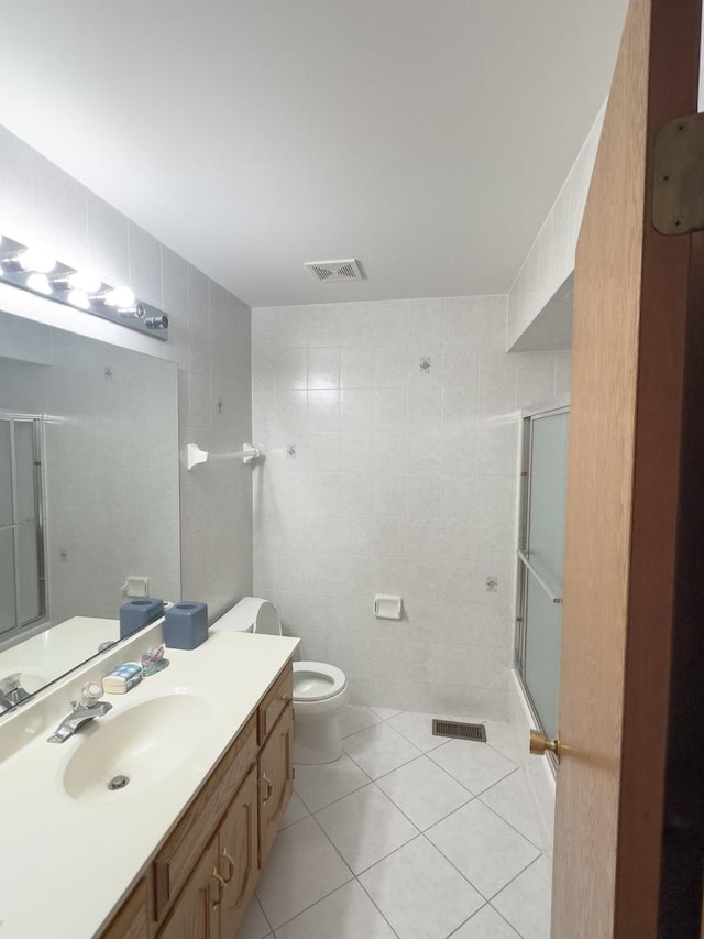 full bath with tile walls, toilet, an enclosed shower, vanity, and tile patterned flooring