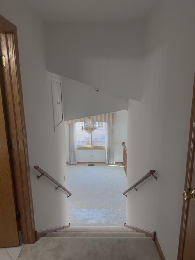 staircase featuring carpet floors, baseboards, and vaulted ceiling