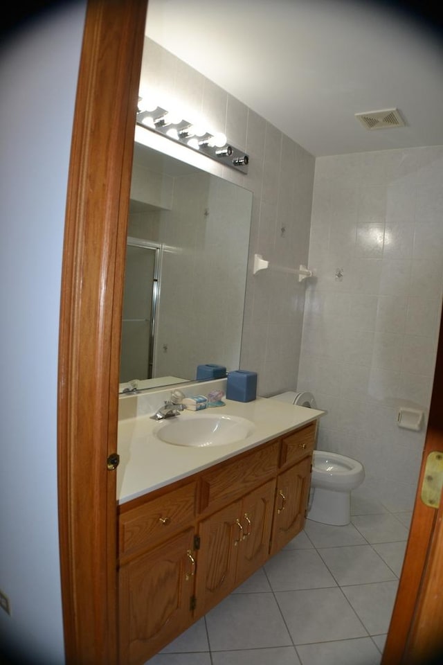 bathroom with tile walls, tile patterned flooring, vanity, walk in shower, and toilet