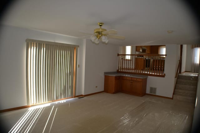 unfurnished living room featuring light colored carpet and ceiling fan