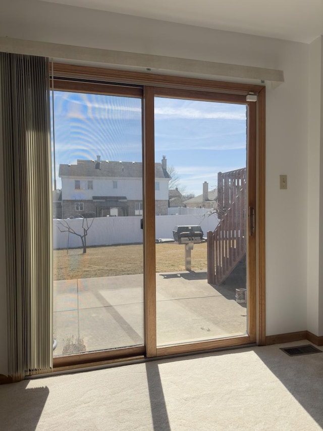 doorway featuring baseboards, visible vents, plenty of natural light, and carpet flooring