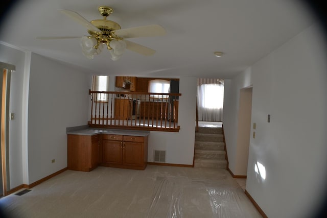 kitchen with ceiling fan and light carpet