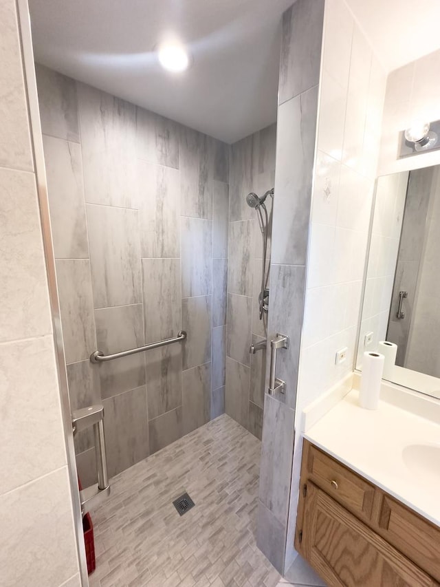 bathroom with tiled shower and vanity