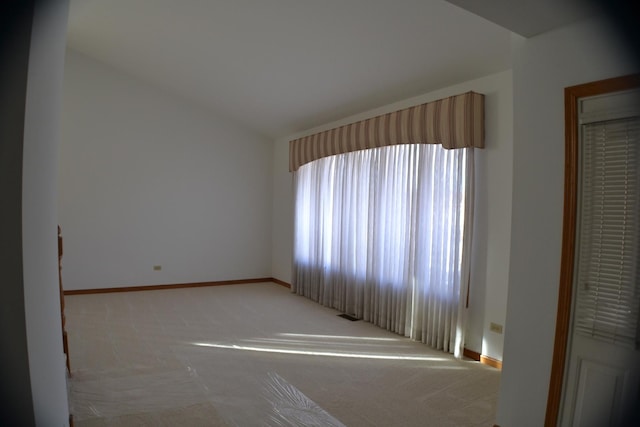 empty room featuring vaulted ceiling and light colored carpet