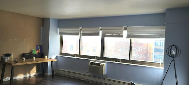 interior space featuring a baseboard heating unit, a wall mounted air conditioner, and hardwood / wood-style floors