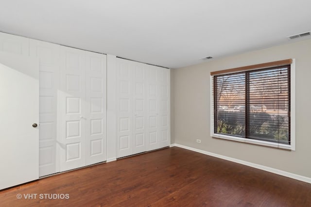 unfurnished bedroom with multiple closets and dark wood-type flooring