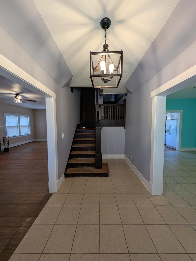 staircase featuring ceiling fan with notable chandelier and tile patterned flooring