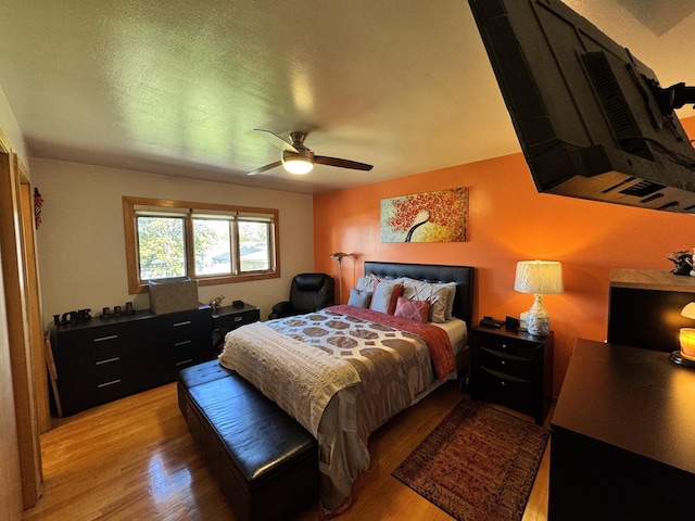 bedroom with ceiling fan, a textured ceiling, and light wood-type flooring