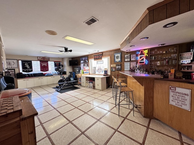 bar featuring ceiling fan and wood walls