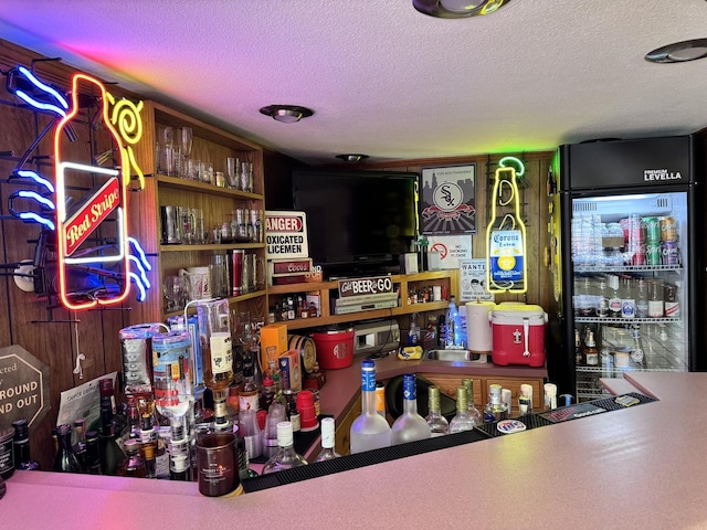 bar featuring a textured ceiling and fridge