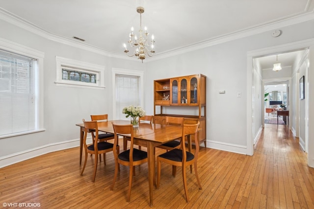 dining space with a notable chandelier, light hardwood / wood-style flooring, and ornamental molding