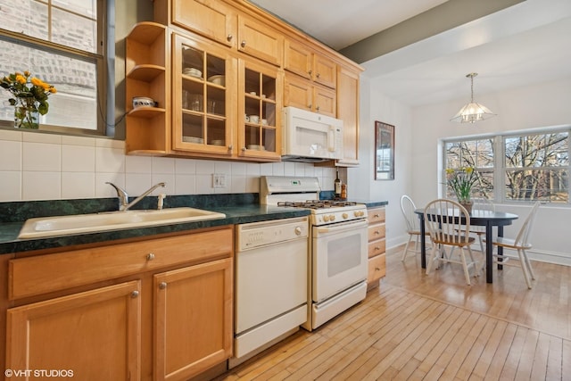 kitchen with tasteful backsplash, sink, white appliances, and light hardwood / wood-style flooring