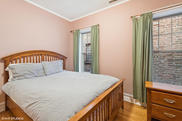 bedroom featuring ornamental molding and light hardwood / wood-style floors