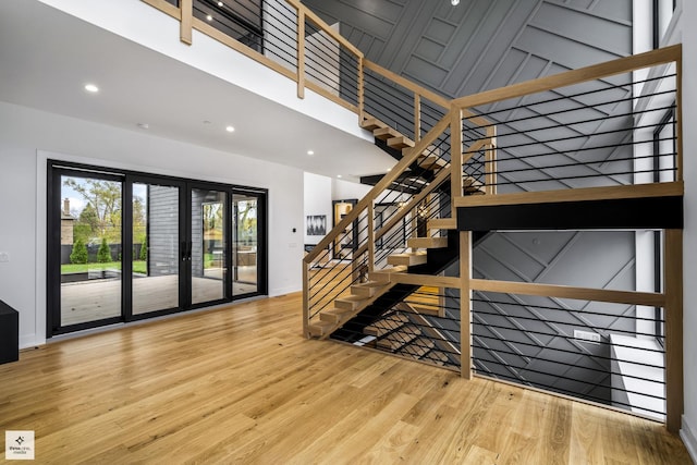 stairway with french doors, wood-type flooring, and a high ceiling