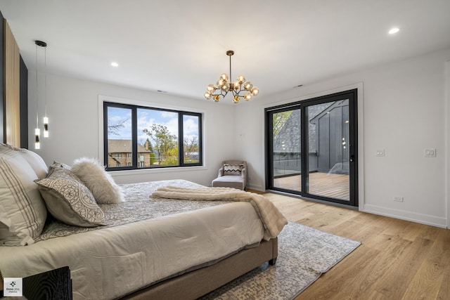 bedroom featuring access to exterior, multiple windows, light hardwood / wood-style flooring, and an inviting chandelier