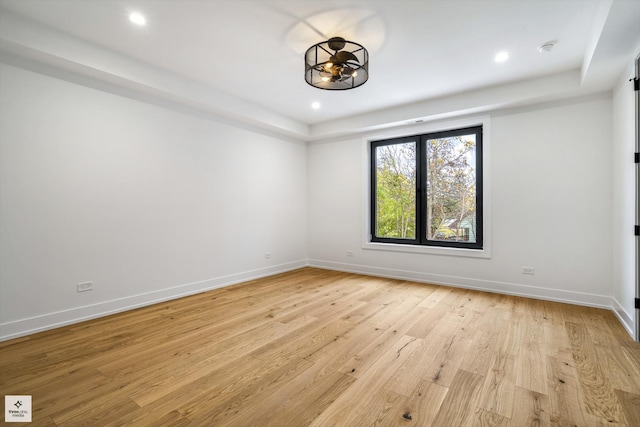 spare room with light wood-type flooring and a raised ceiling