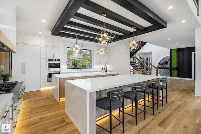 kitchen with white cabinets, decorative light fixtures, beamed ceiling, a large island, and a breakfast bar