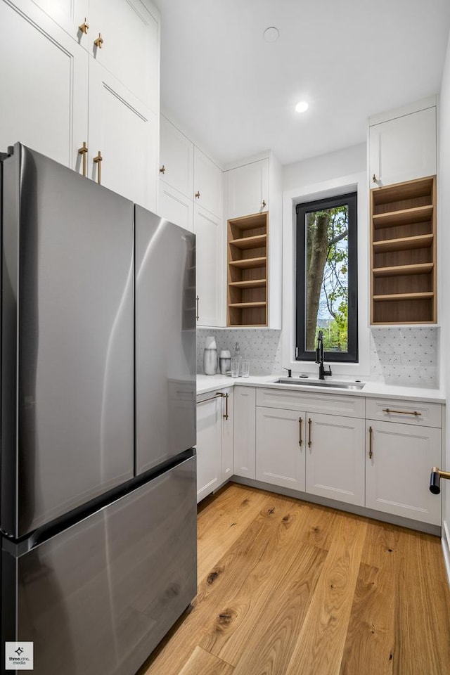 kitchen featuring sink, stainless steel refrigerator, decorative backsplash, and white cabinetry