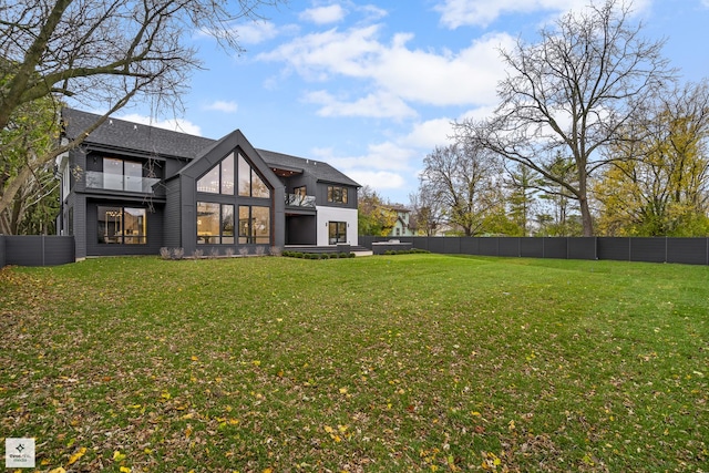 back of property featuring a balcony and a yard