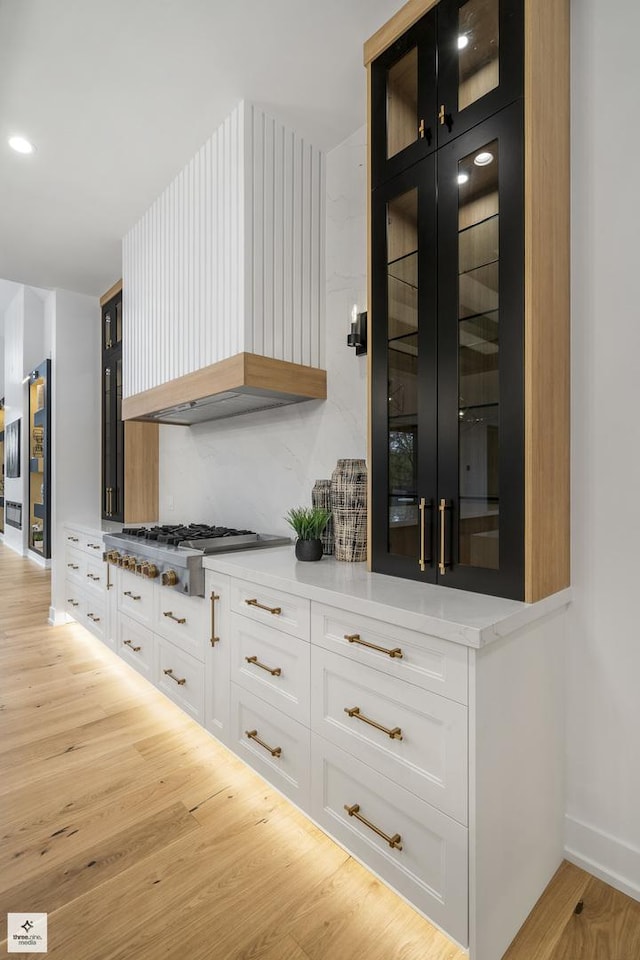 kitchen with white cabinets, stainless steel gas stovetop, premium range hood, and light hardwood / wood-style floors