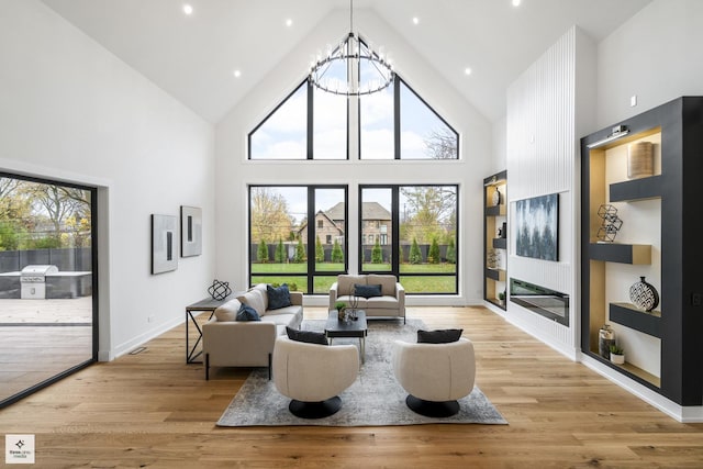 living room featuring a chandelier, a towering ceiling, and light wood-type flooring