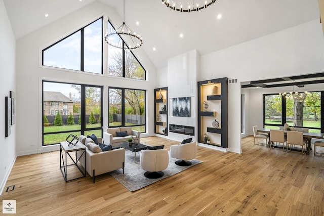 living room featuring light wood-type flooring, high vaulted ceiling, and a notable chandelier