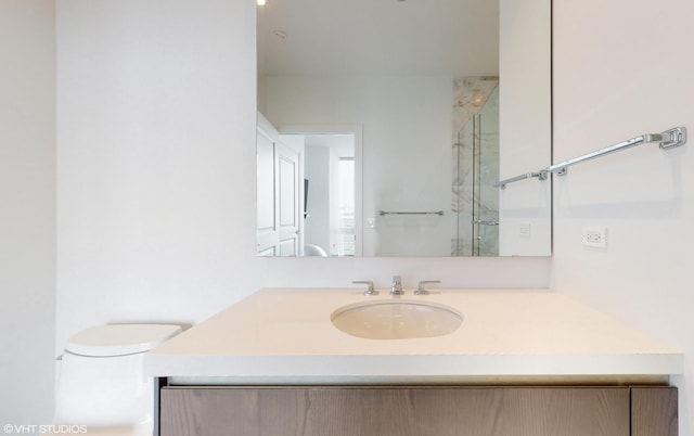 bathroom featuring toilet, a shower with door, and vanity